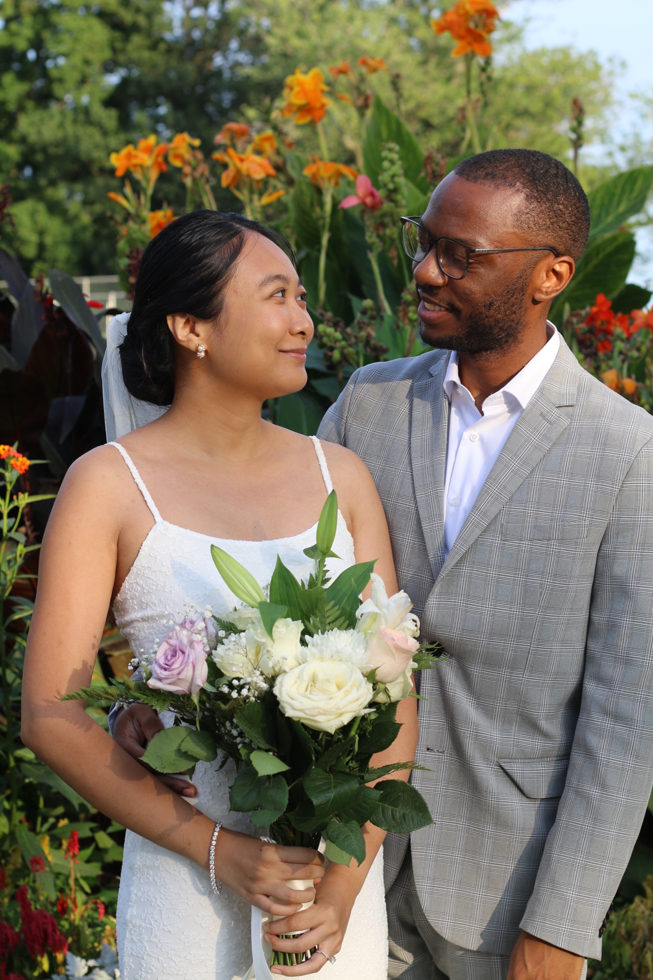 Krishel and Omar smile at each other in a garden of orange flowers.
